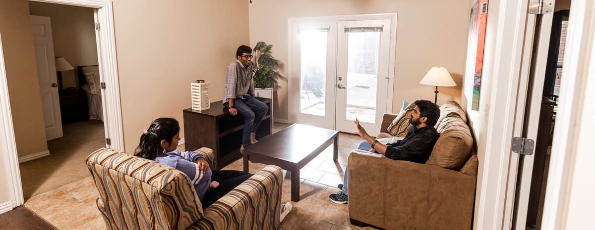 Three international students relax and talk in an on-campus apartment