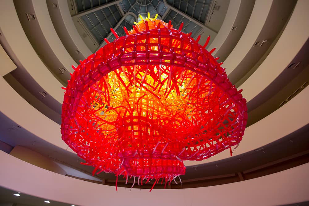 A red and yellow conical art piece hangs inside a spiraling museum space