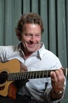A smiling man plays an acoustic guitar. A smiling man plays an acoustic guitar.