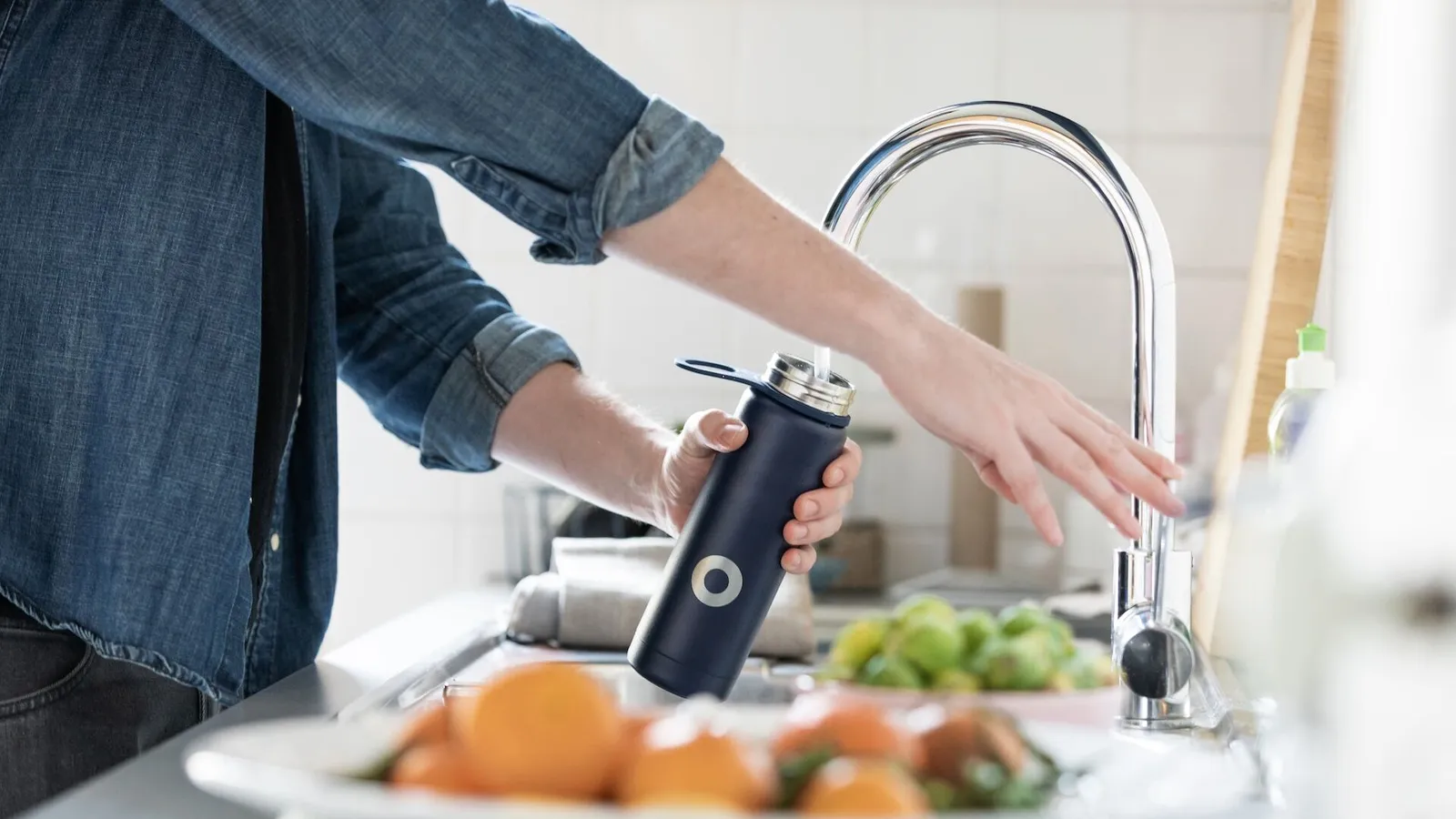 Filling water bottle with fruit in foreground