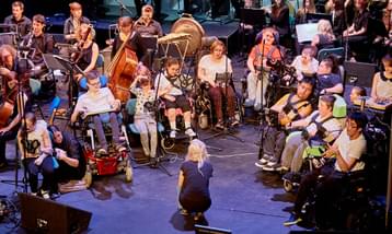 Young musicians in wheelchairs performing on stage using iPads