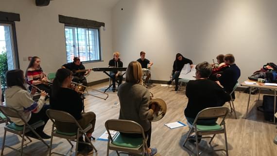 A group of musicians sat in a circle playing instruments