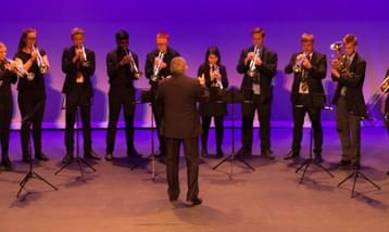 A row of brass players performing on a stage.