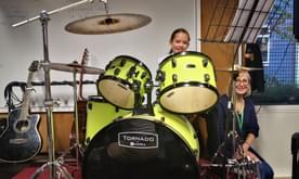 young girl smiling behind large drums
