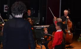 A young boy conducts the orchestra.