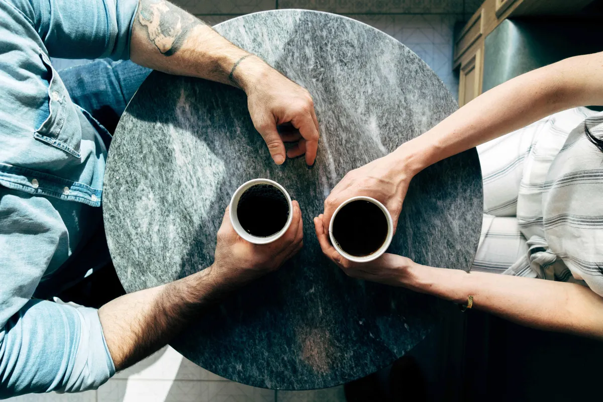 Two people sitting at a table with coffee in their hands