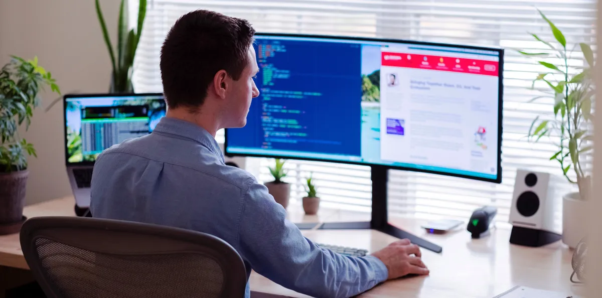 Man in blue shirt looking at a curved computer monitor