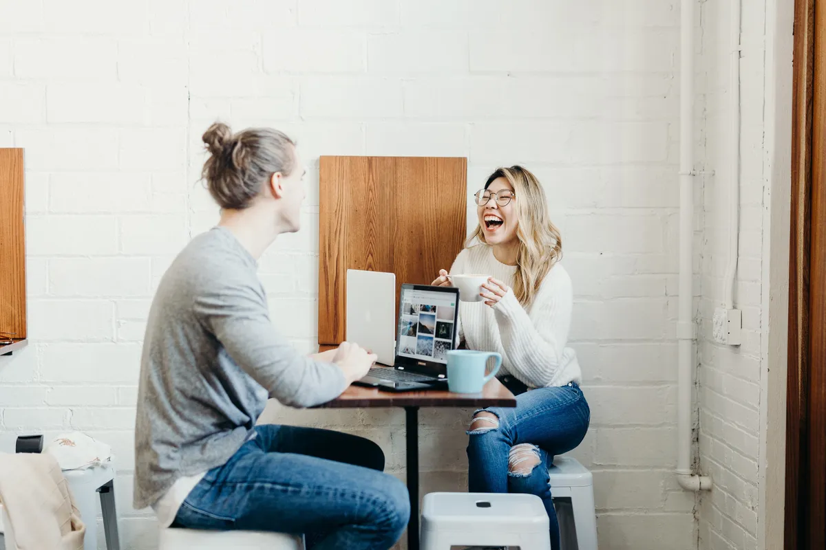 man-and-woman-smiling-at-a-coffee-meeting-with-laptops