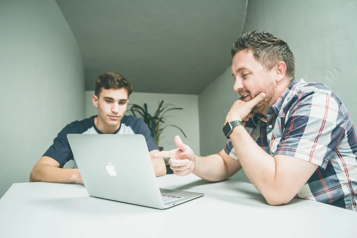 Middle aged man and young boy look at a laptop