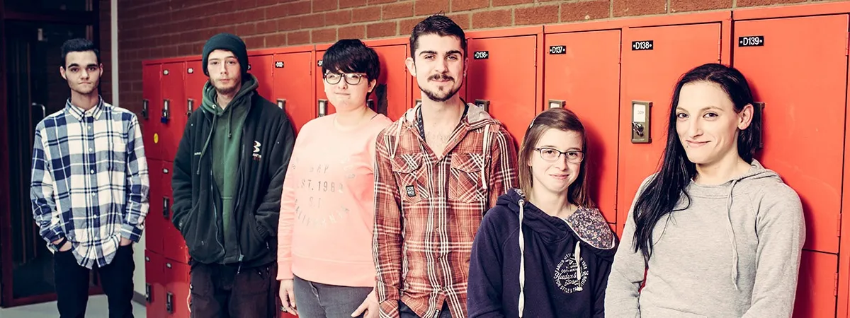 Group of teenagers standing in front of red lockers