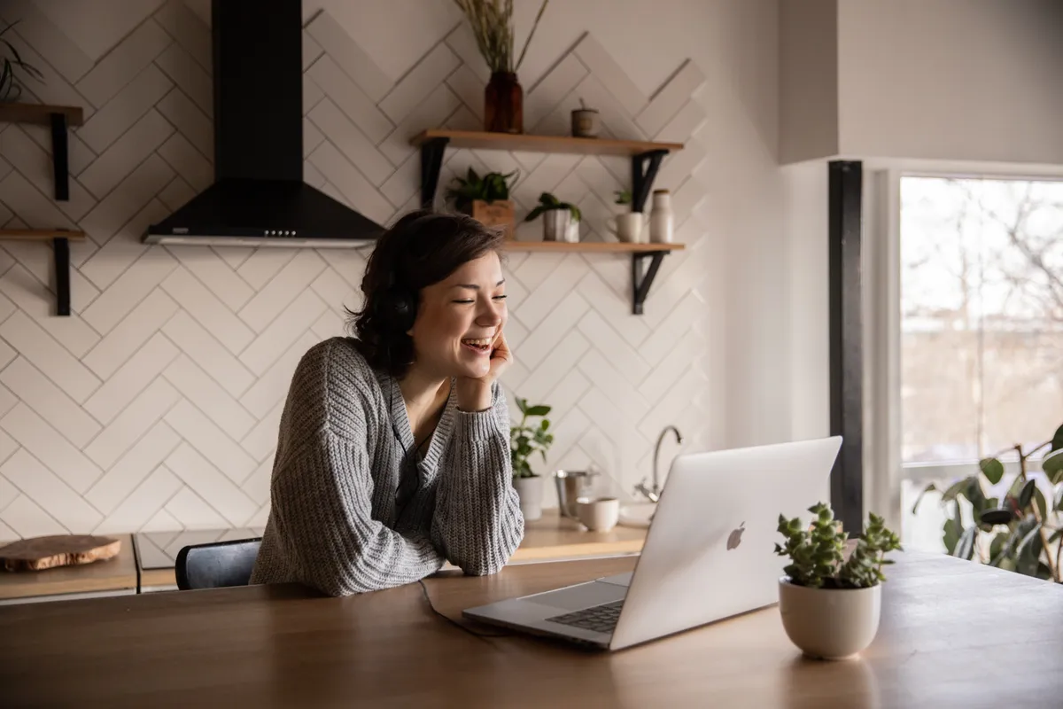 Smiling woman talking via laptop in kitchen 4049992