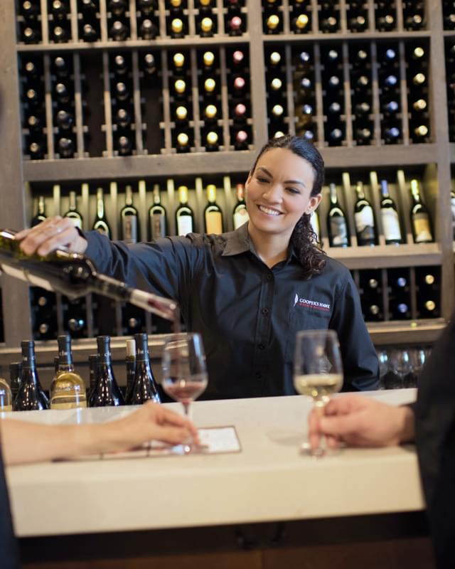 A woman is pouring wine at a wine bar.