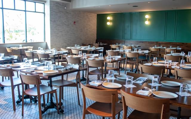 A dining room full of tables and chairs set for a meal.