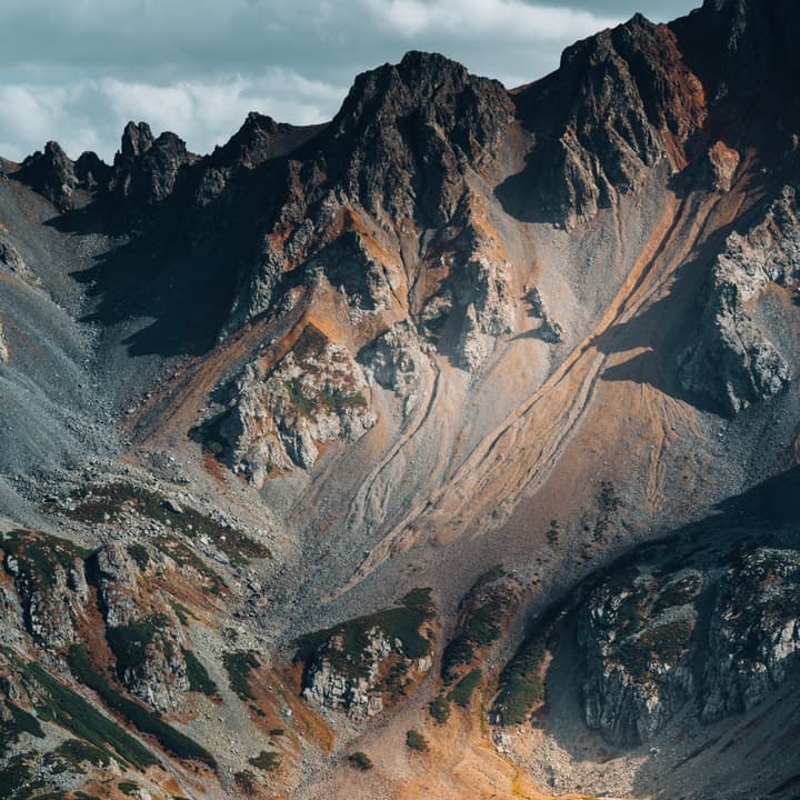 Rays of sunshine break through thick clouds to illuminate a majestic mountain range.