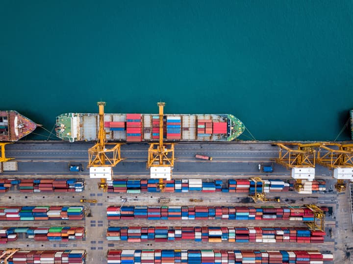Aerial view of shipping containers and a ship in the water.