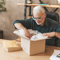An older, white man opens a package for an online purchase.