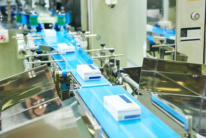 A conveyer belt in a medication production facility is loaded with packages of recently manufactured medication.