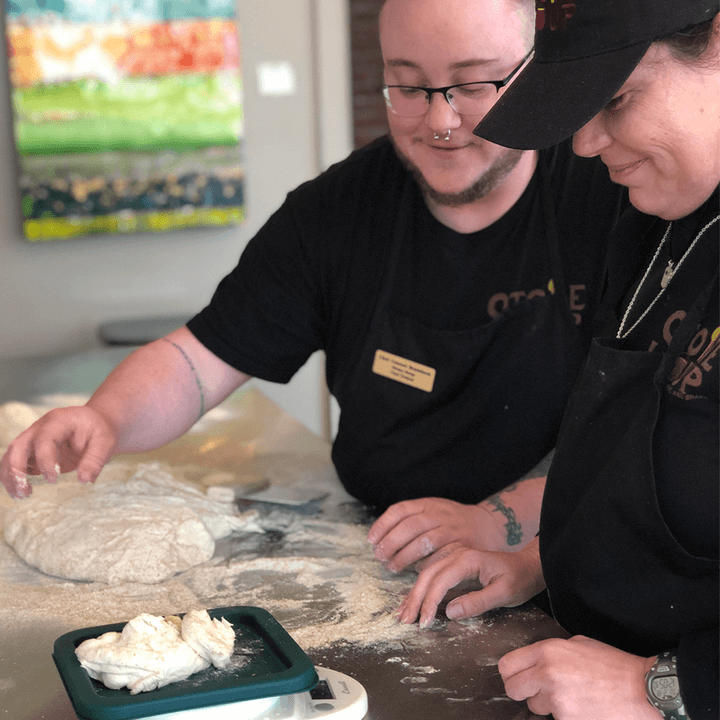 Connor Braddock (left) shows Pam Ward (right) how to knead dough in Stone Soup's Portland kitchen.