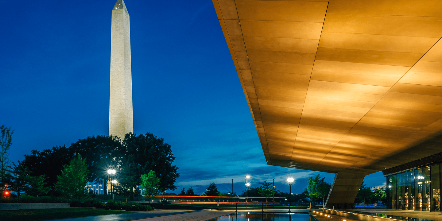 An image taken from the front of the National Museum of African American History and Culture in Washington, DC shortly after sunset. The Washington Monument is in the background.