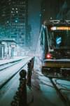 A light rail train travels through snowy downtown Minneapolis at night