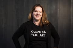 An image of Propeller co-founder and CEO Amy Weeden. She is wearing a black blazer over a black t-shirt that has "Come as you are." written on it in a white, sans serif font.