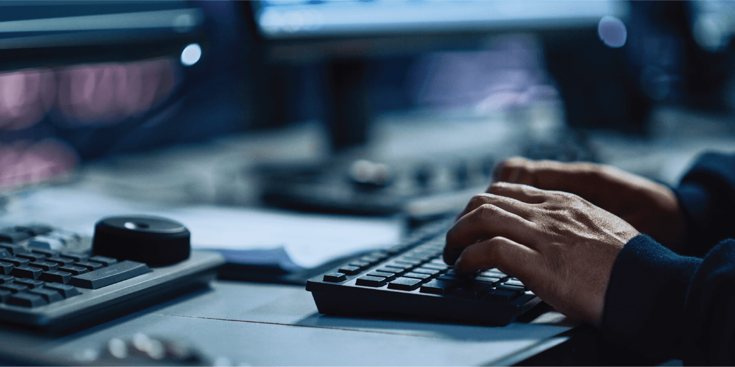 A close-up on a person's hands typing on a keyword at a computer