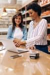 Store owners use laptops to discuss business objectives