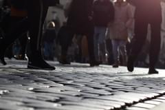 The lower half of people walking on a cobble stone road