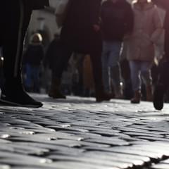 The lower half of people walking on a cobble stone road