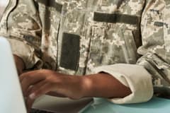 A close-up of a veteran wearing fatigues while typing at a computer