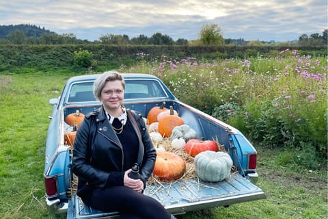 Candid image of Propeller employee Renae Roemmich sitting on the back of an El Camino, the bed of which is full of various colors of pumpkins. Profile Photo