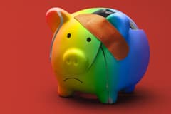 A cracked, rainbow-colored piggy bank is held together with a bandage, and the piggy bank's mouth is frowning. The background is solid red.