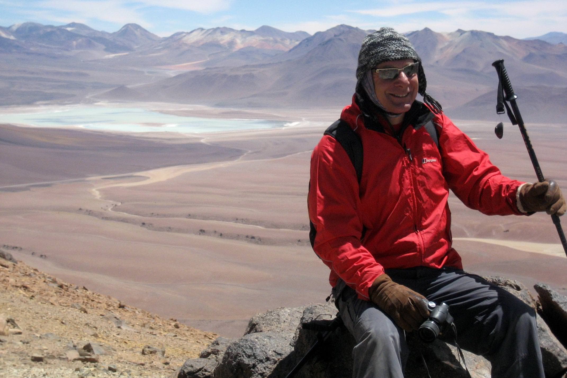 Chile atacama desert man in red sitting at summit of toco volcano