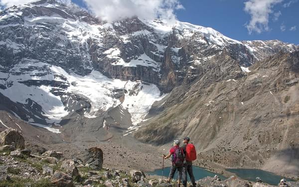 Trekkers enjoy the scenery, looking up the huge north face of Mirali Peak