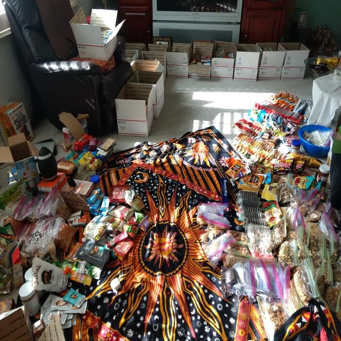 Resupply boxes:  Food representing roughly 60 days of hunger prevention spreads across the living room floor before being carefully packaged in resupply boxes.