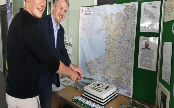 Huw Irranca-Davies and Will Renwick cut the cake at the Cambrian Way book launch