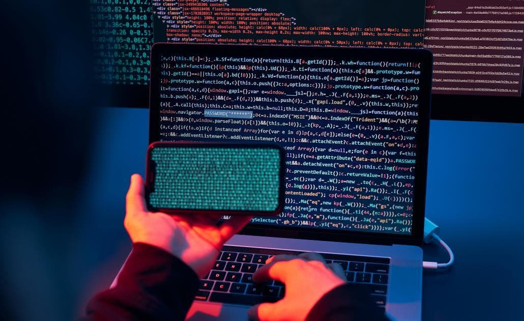 Hacker with computer and smartphone