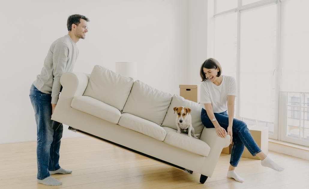 Man lifting sofa with dog