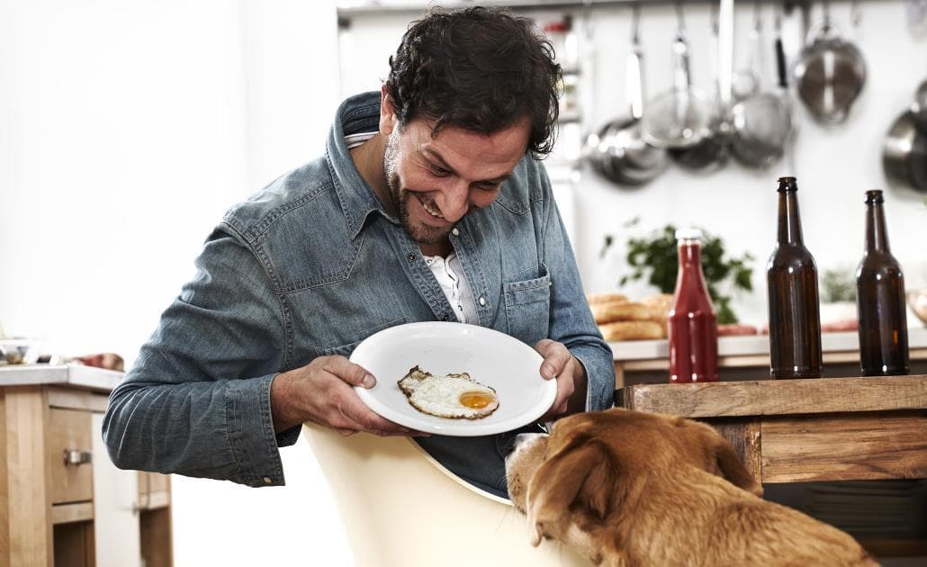 Man showing egg to dog