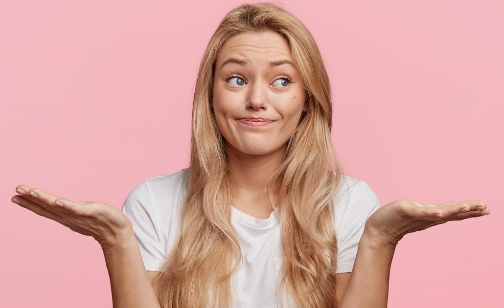 Woman shrugging on pink background