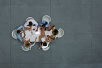 Aerial of diverse team sitting at conference table in a meeting