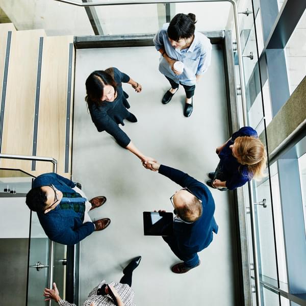 Aerial of businesspeople in suites shaking hands.