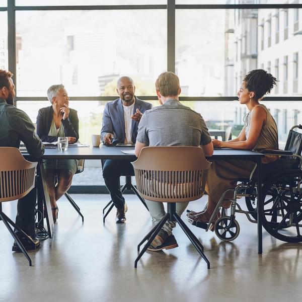 Group of diverse corporate workers in teamwork conversation sharing ideas at the workplace