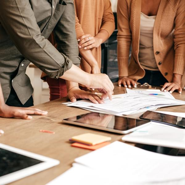 businesspeople standing around a table during a meeting