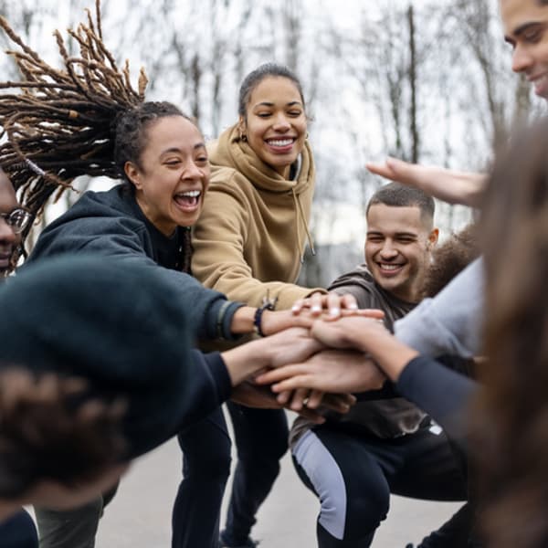 diverse group of young adults circled together in a park