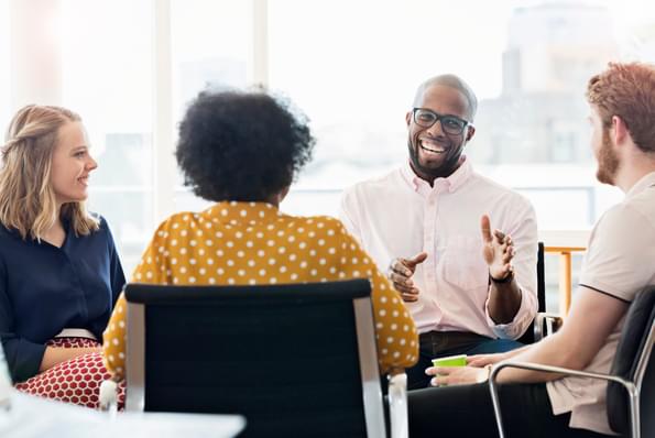 people sitting around a table and laughing during a work meeting