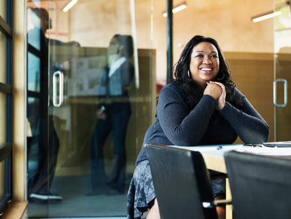 smiling woman sitting alone at an office table