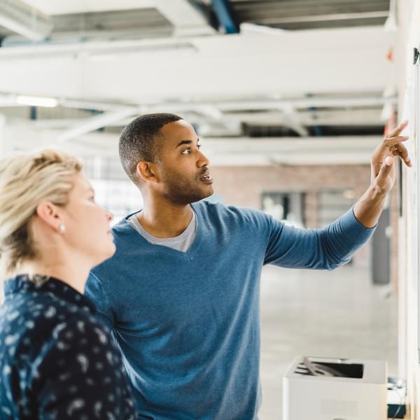 two people reviewing a whiteboard during a meeting