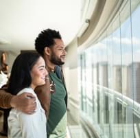 Young happy couple enjoying while looking through window in a hallway.