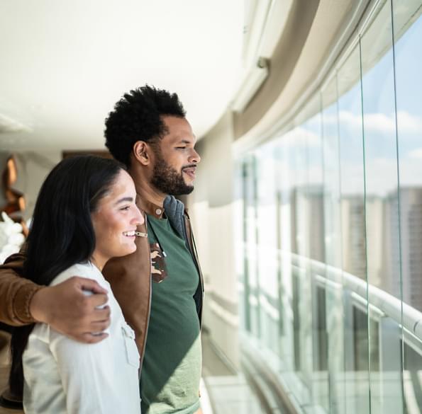 Young happy couple enjoying while looking through window in a hallway.